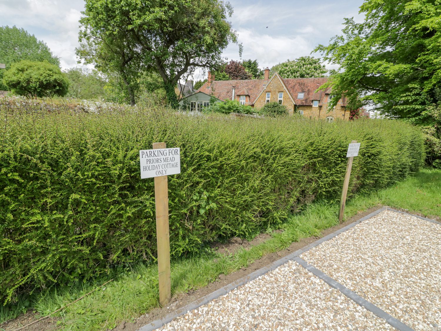 A gravel parking area with signs indicating Priors Mead holiday cottage only near a hedge and trees at Priors Mead in Claydon near Cropredy