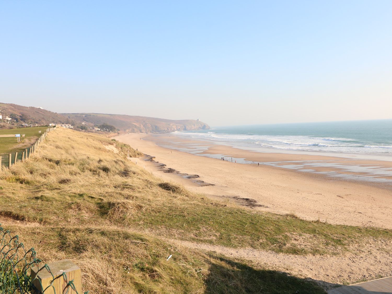 A sandy beach with waves and grass dunes along the shore at Palm Lodge in Praa Sands