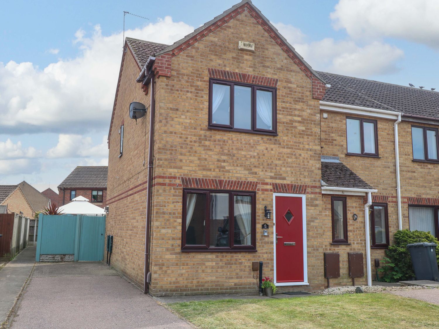 A house with a red door and garden at Breydon Cottage in Bradwell near Gorleston-On-Sea