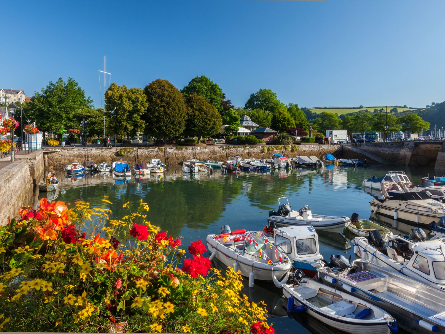 A harbor with boats docked in water and flowers in the foreground at The Borrowers in Dartmouth