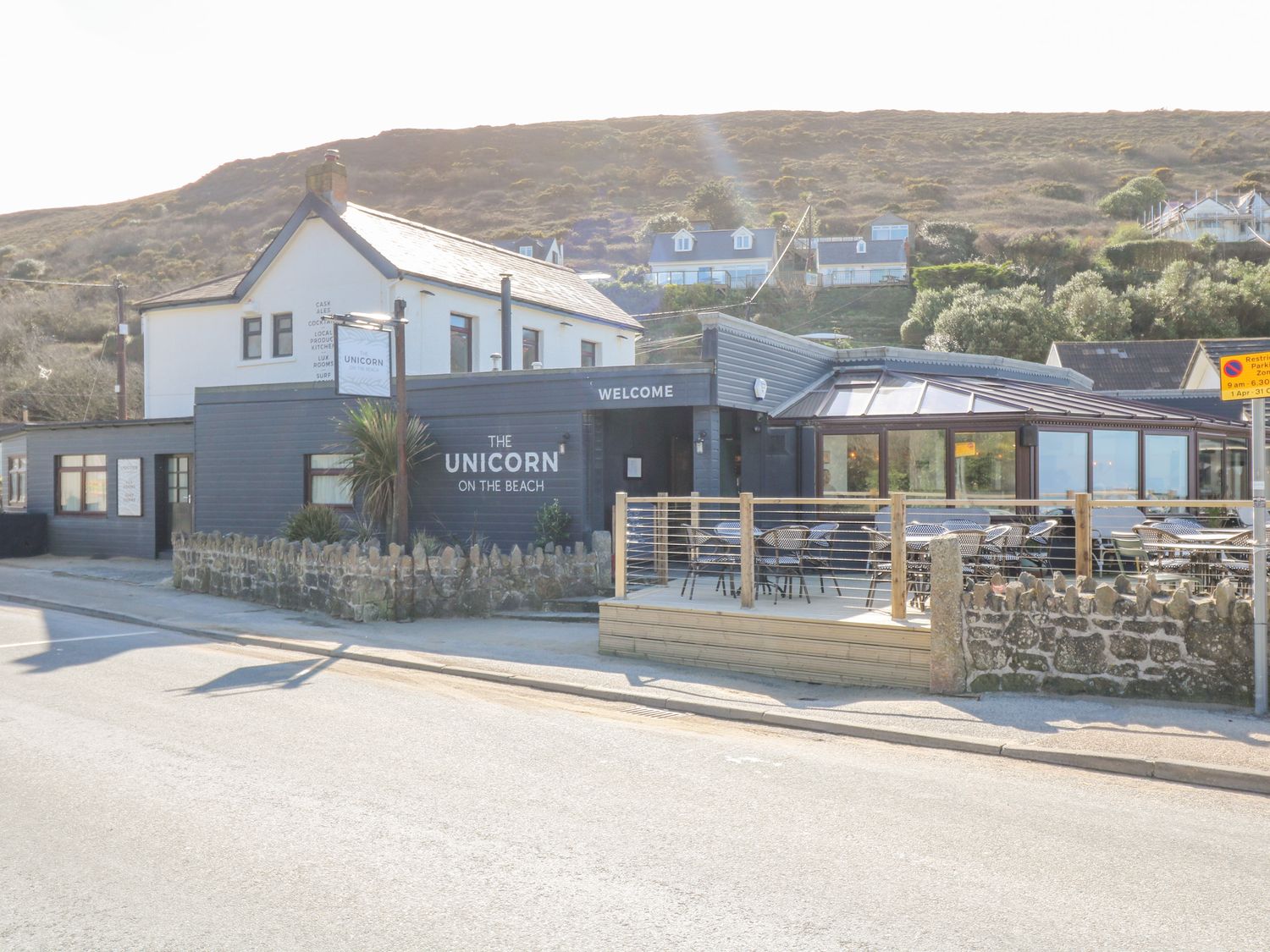 A building with a sign reading The Unicorn on the Beach with an outdoor seating area at Sea Breeze 17 Gannel in Porthtowan