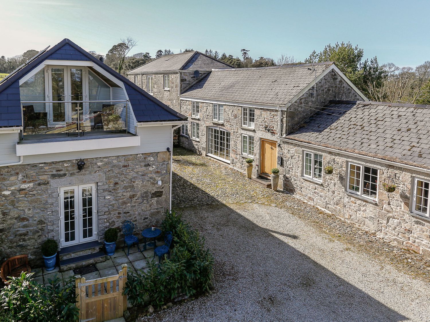 A courtyard with stone buildings and outdoor seating at Poppyfields Stable in St Day near Porthtowan