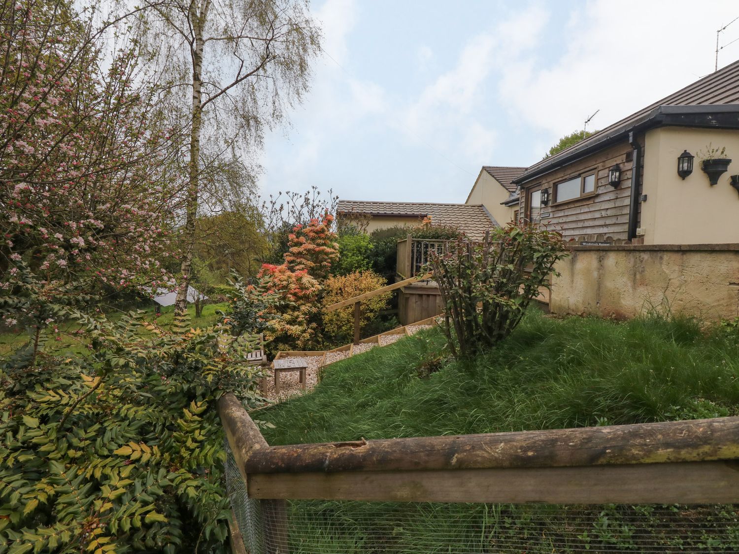A garden with various plants and a wooden fence next to a house at Woodstock Retreat in Birchill near Chardstock