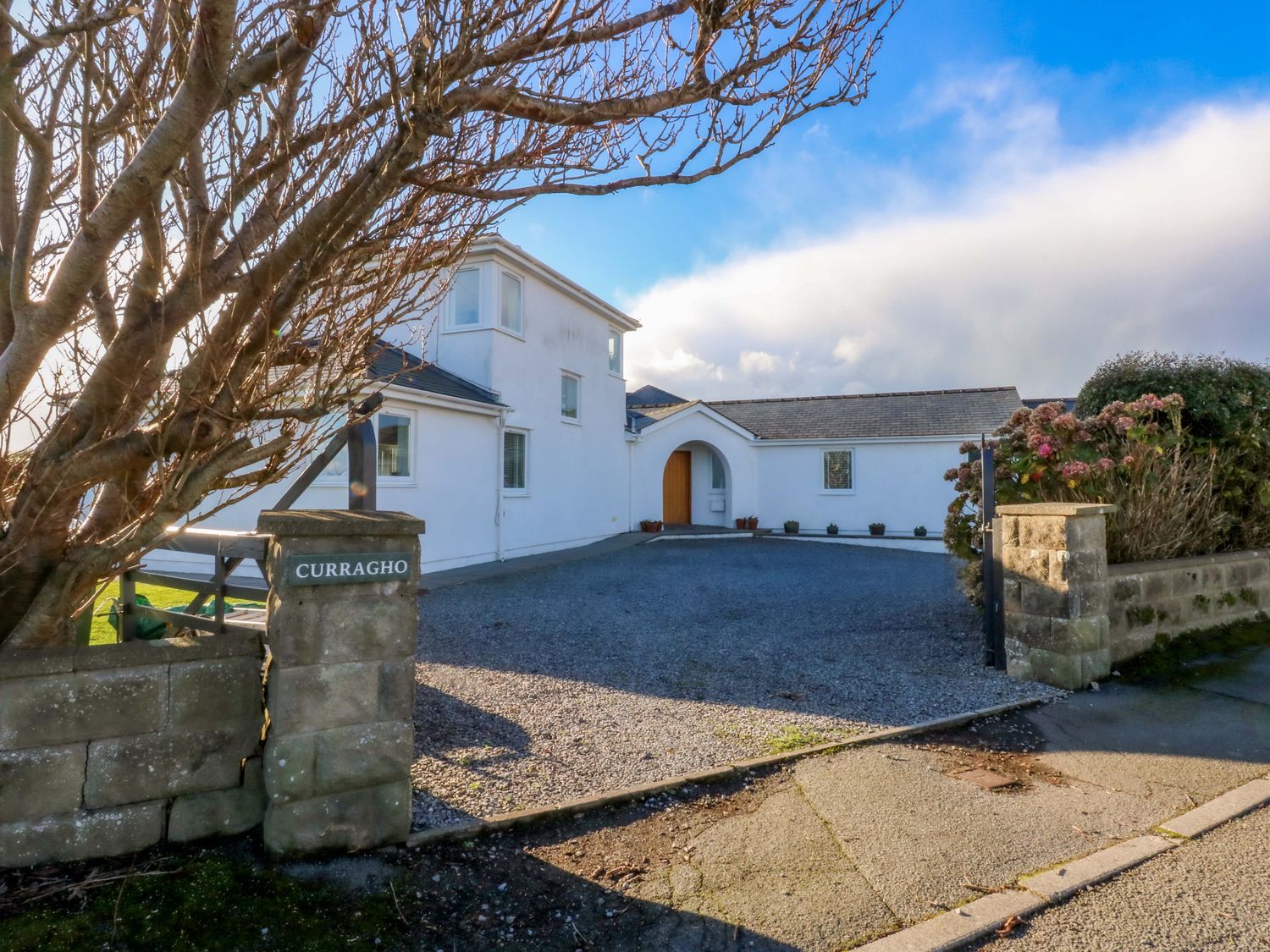 A house with a gravel driveway and gate at Curragho in Trearddur Bay