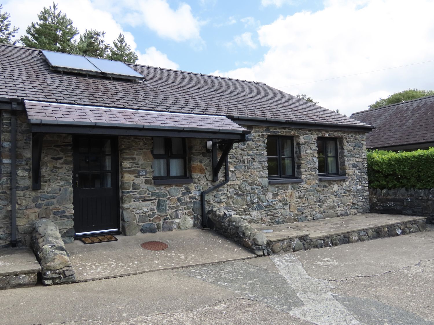 A stone building with solar panels at Bryn Eira Tack Room in Llanfair PG