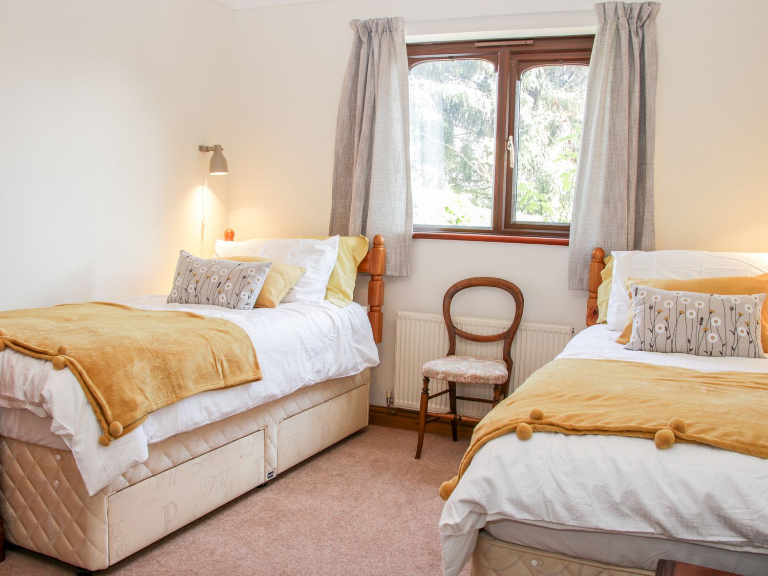 A bedroom with two single beds a wooden chair and a window with curtains at Court Farm in Neen Sollars near Cleobury Mortimer