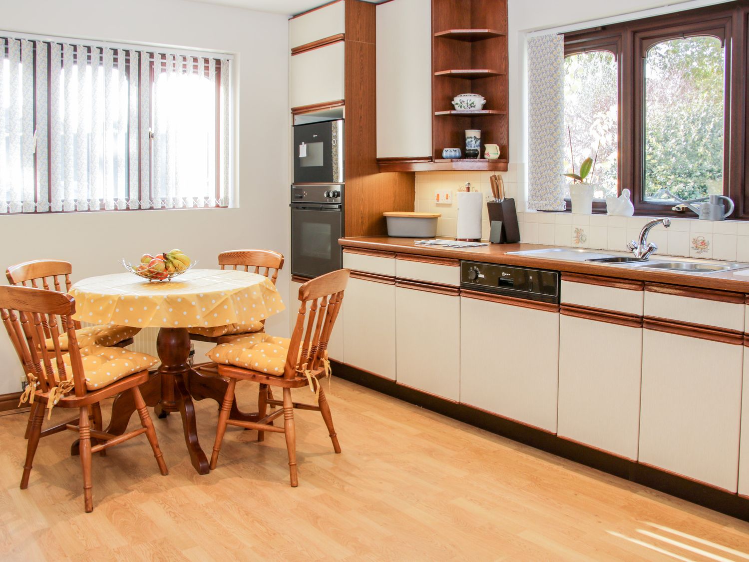 A kitchen with a round table and four chairs with cushions next to a window and cabinets with appliances at Court Farm Neen Sollars near Cleobury Mortimer