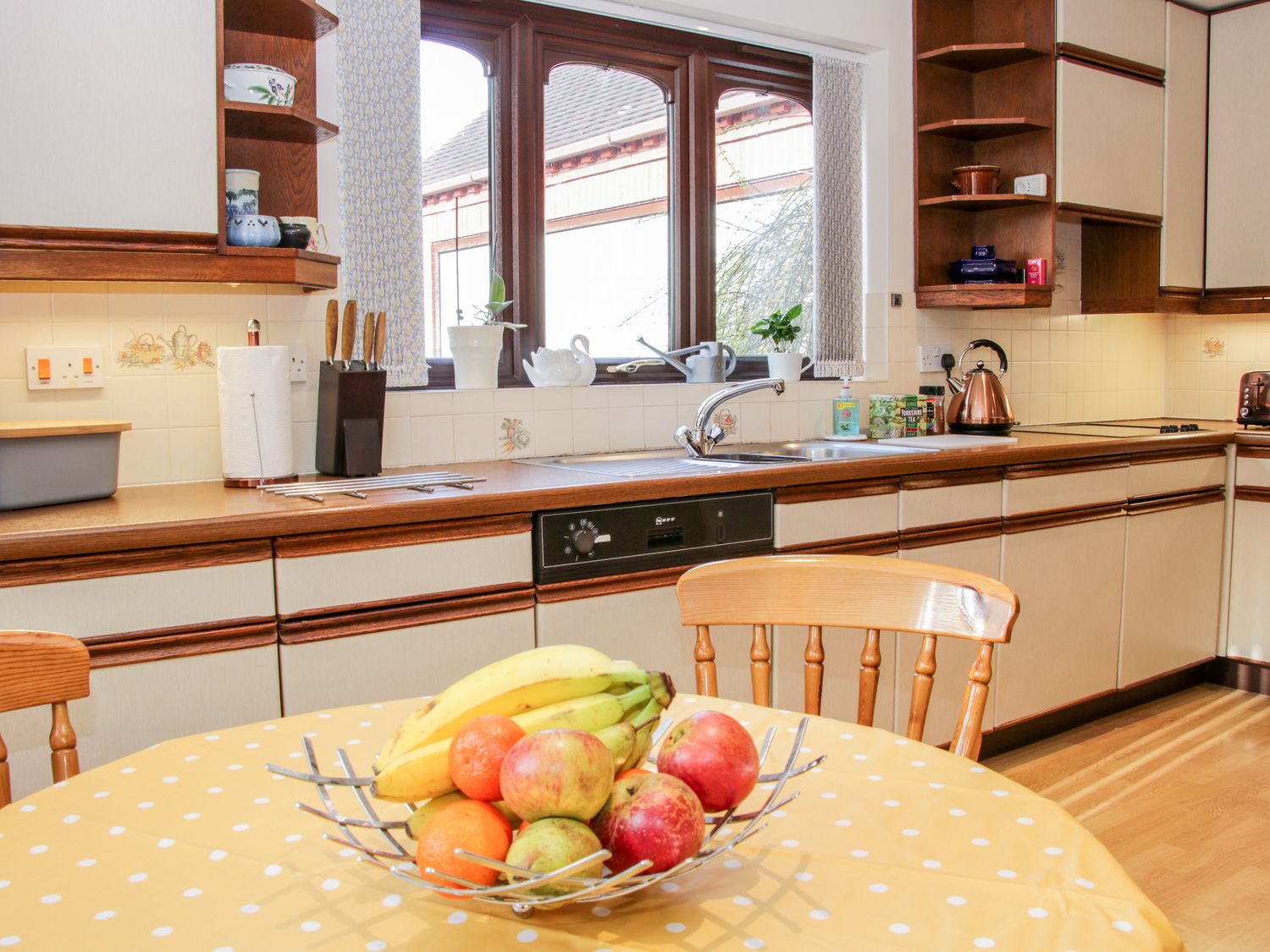 A kitchen with wooden cabinets and a table with a fruit bowl at Court Farm in Neen Sollars near Cleobury Mortimer