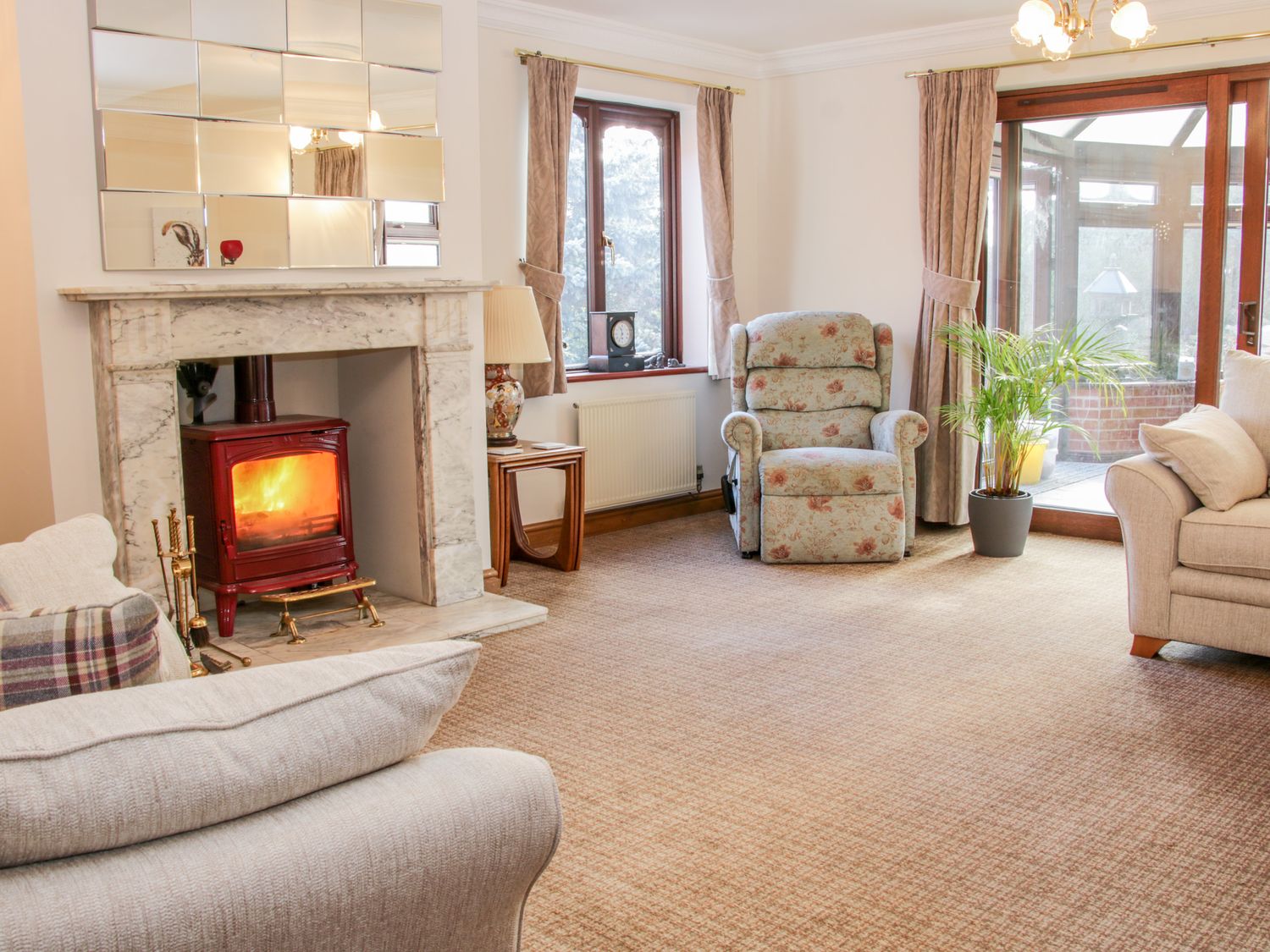 A living room with a fireplace a wood burning stove armchairs a plant and windows at Court Farm Neen Sollars near Cleobury Mortimer