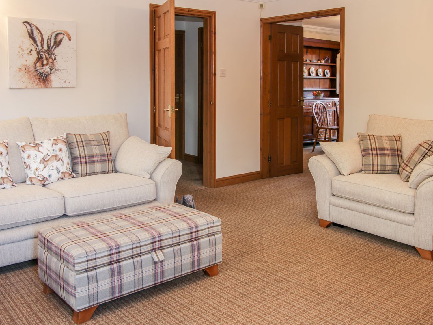 A living room with two beige sofas plaid cushions and a plaid ottoman at Court Farm Neen Sollars near Cleobury Mortimer