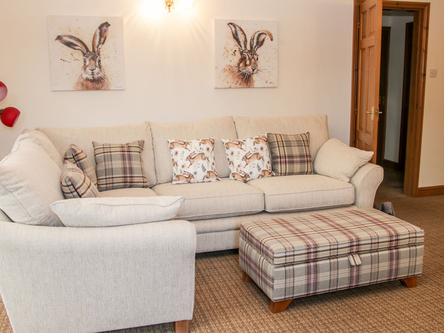 A beige sofa with patterned cushions and a matching plaid ottoman in a living room at Court Farm in Neen Sollars near Cleobury Mortimer