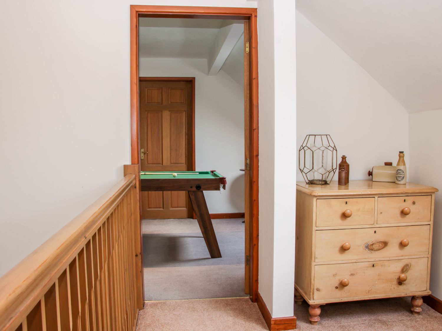 Hallway with wooden railing and dresser next to a doorway showing a room with a pool table at Court Farm in Neen Sollars near Cleobury Mortimer