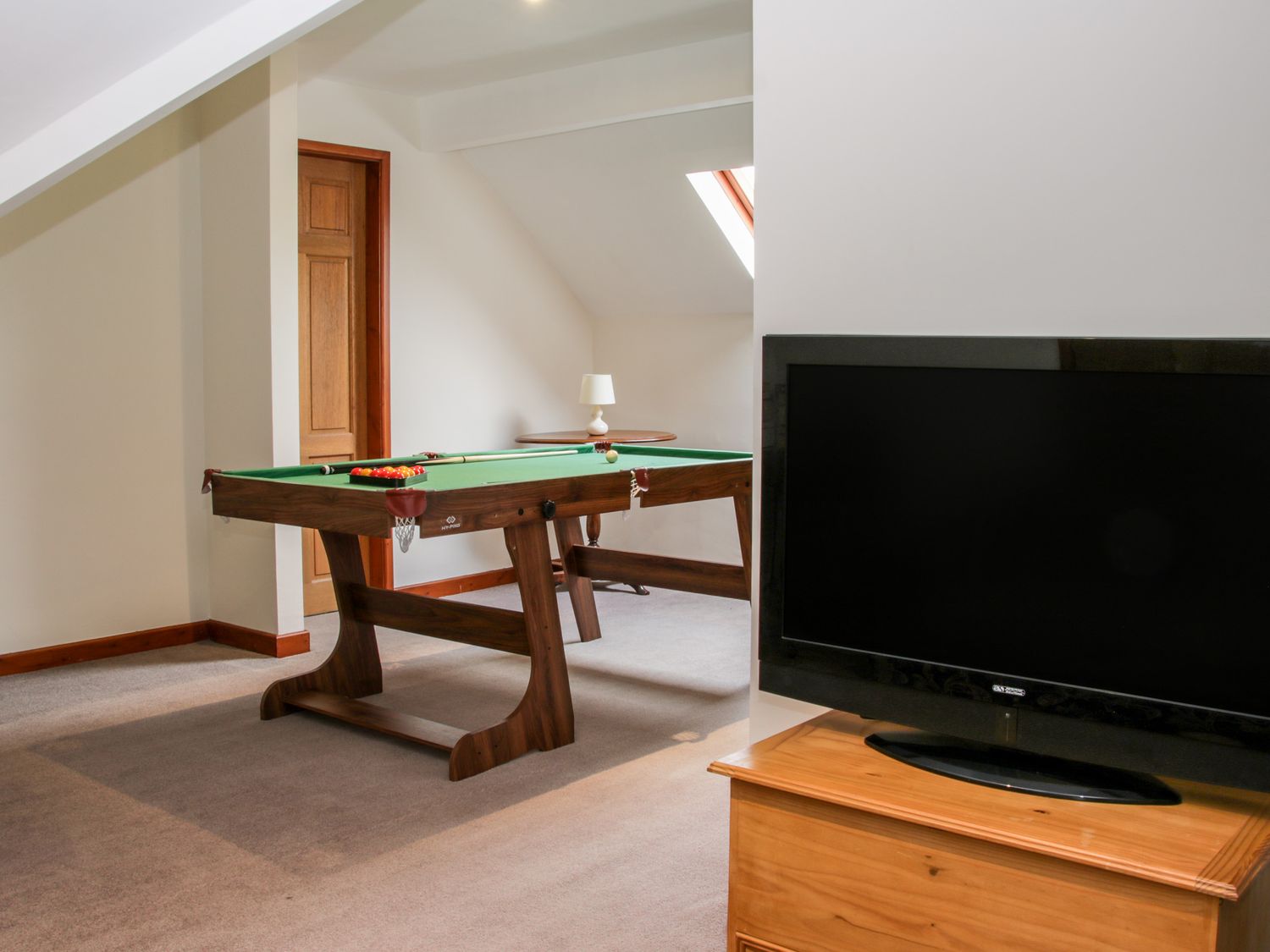 A room with a pool table and a television on a wooden stand at Court Farm in Neen Sollars near Cleobury Mortimer