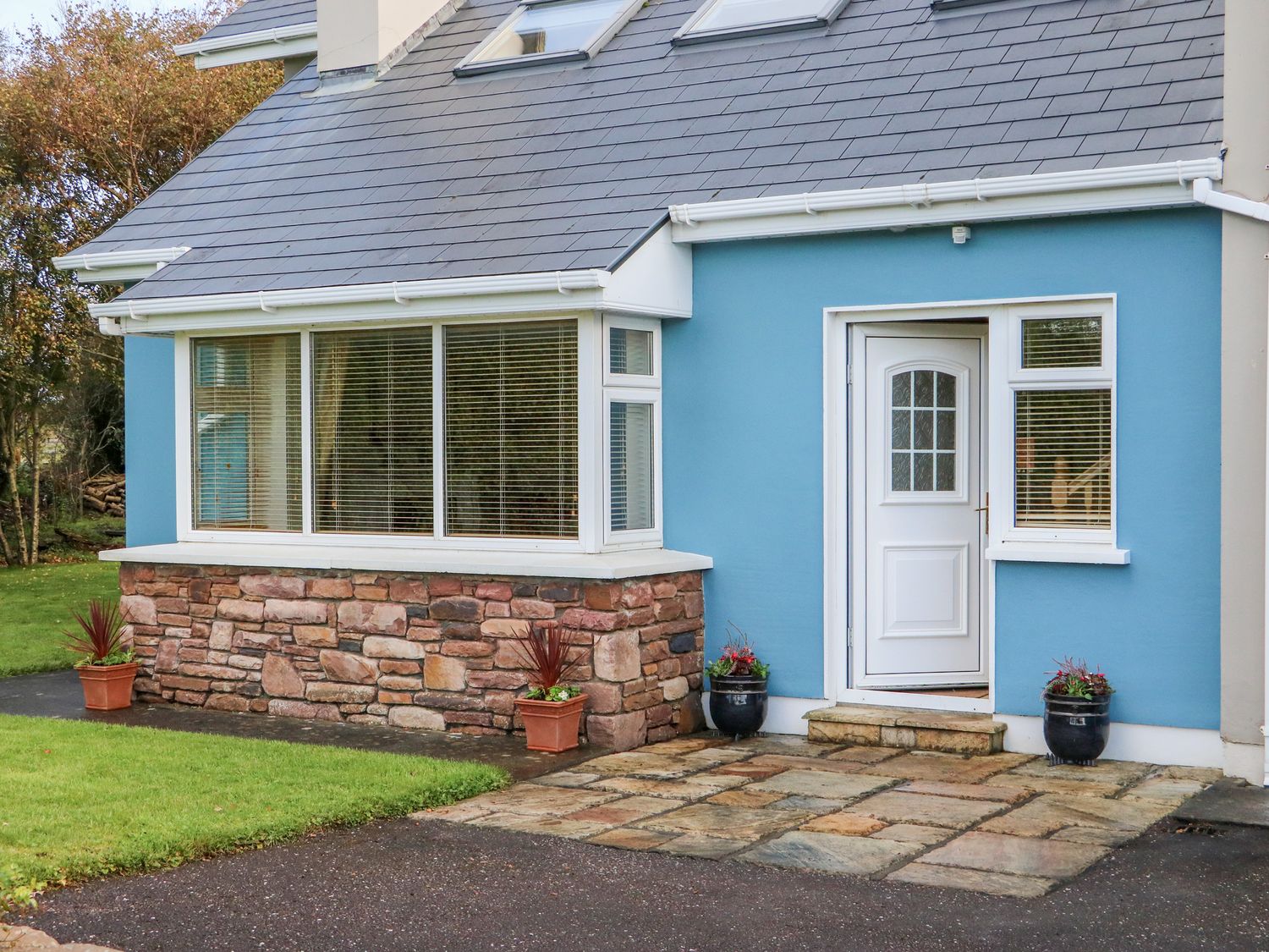 The exterior of a blue house with a white door stone wall base and potted plants at The Blue Annex The Spa near Tralee County Kerry