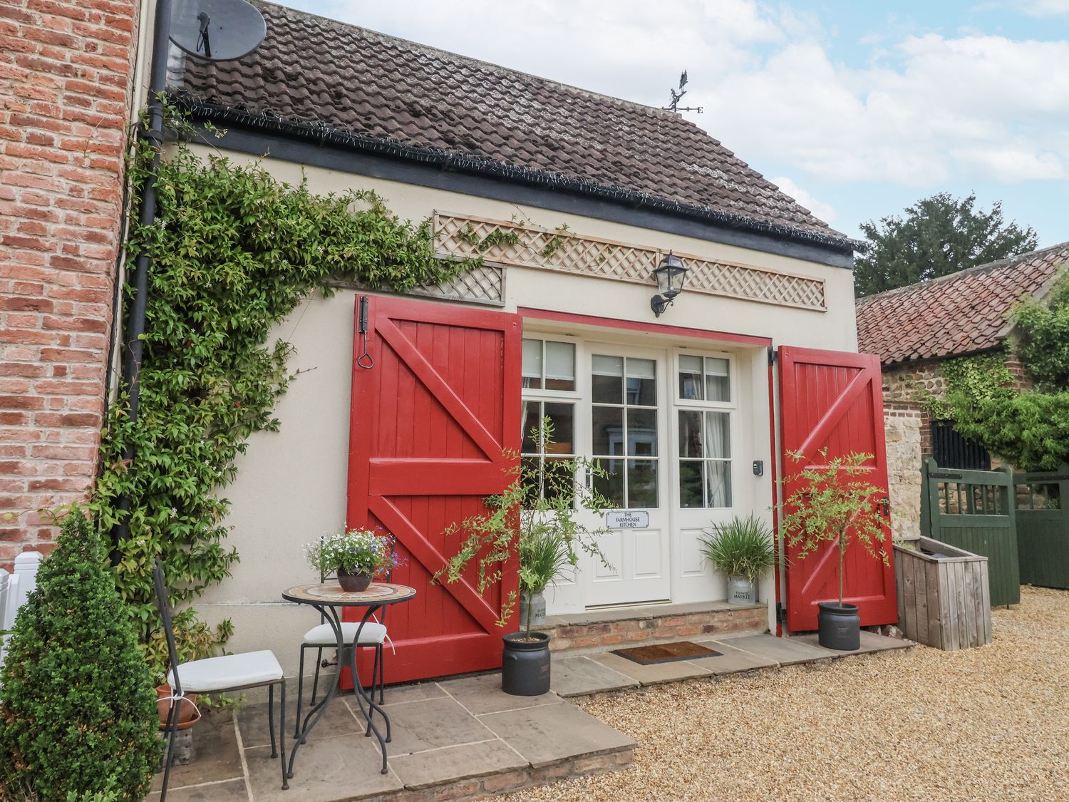 An outdoor area with red doors and a seating arrangement at The Farmhouse Kitchen in Ripon