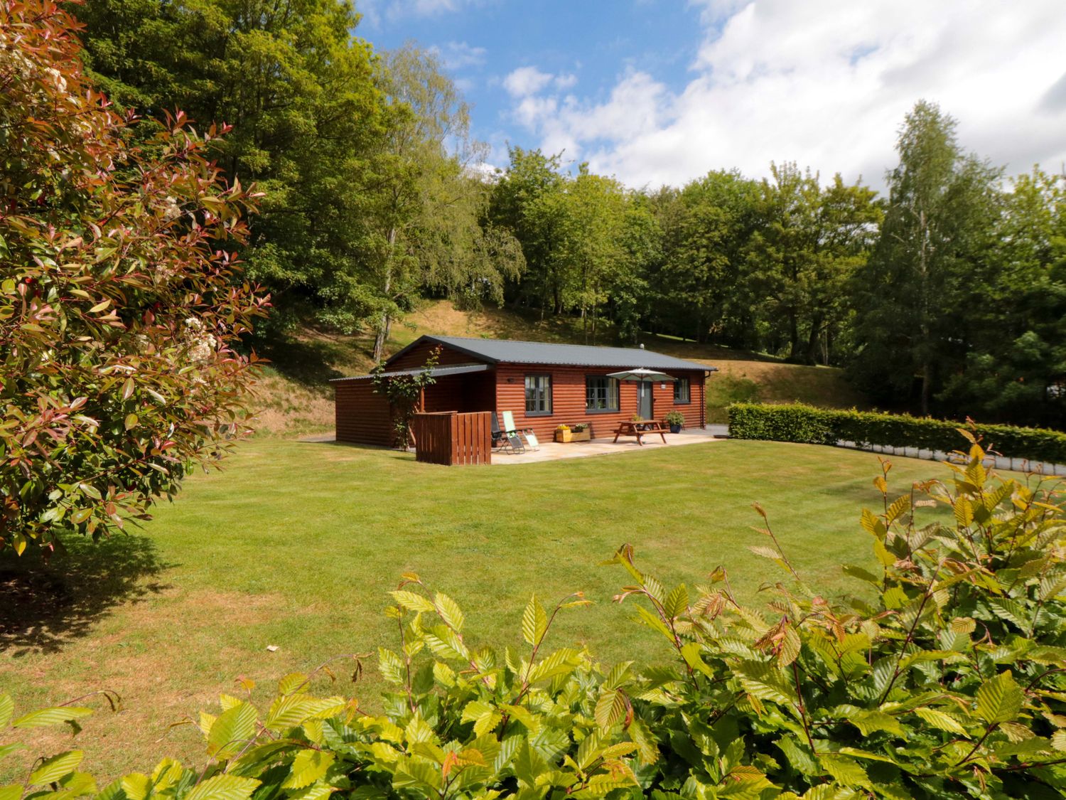 An outdoor garden with a lodge and seating at Ryedale Country Lodges - Willow Lodge in Kirkbymoorside