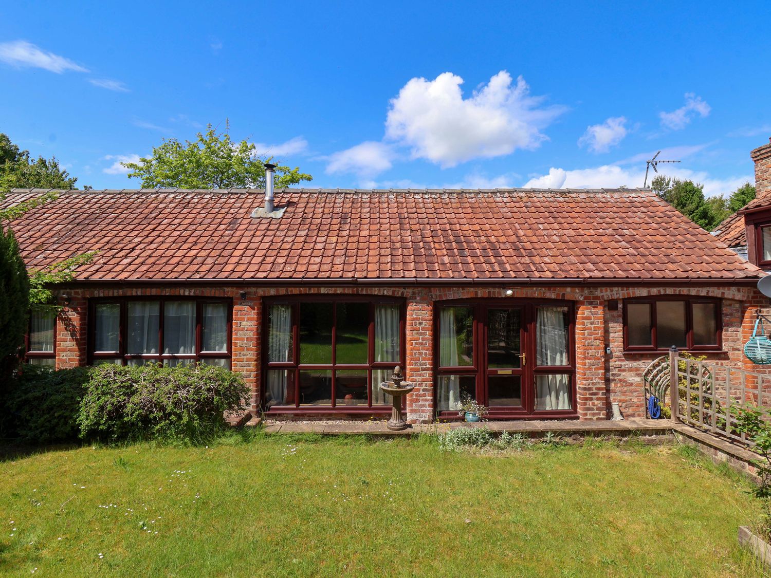 A garden view with brick house and grass at The Stables (2 bed) Driffield