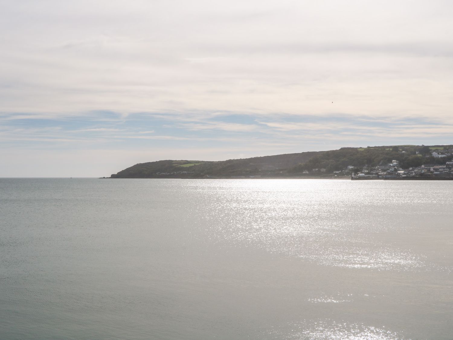 A coastal view with calm water and a hillside with houses in the background at Nana's Cottage in Praze-An-Beeble