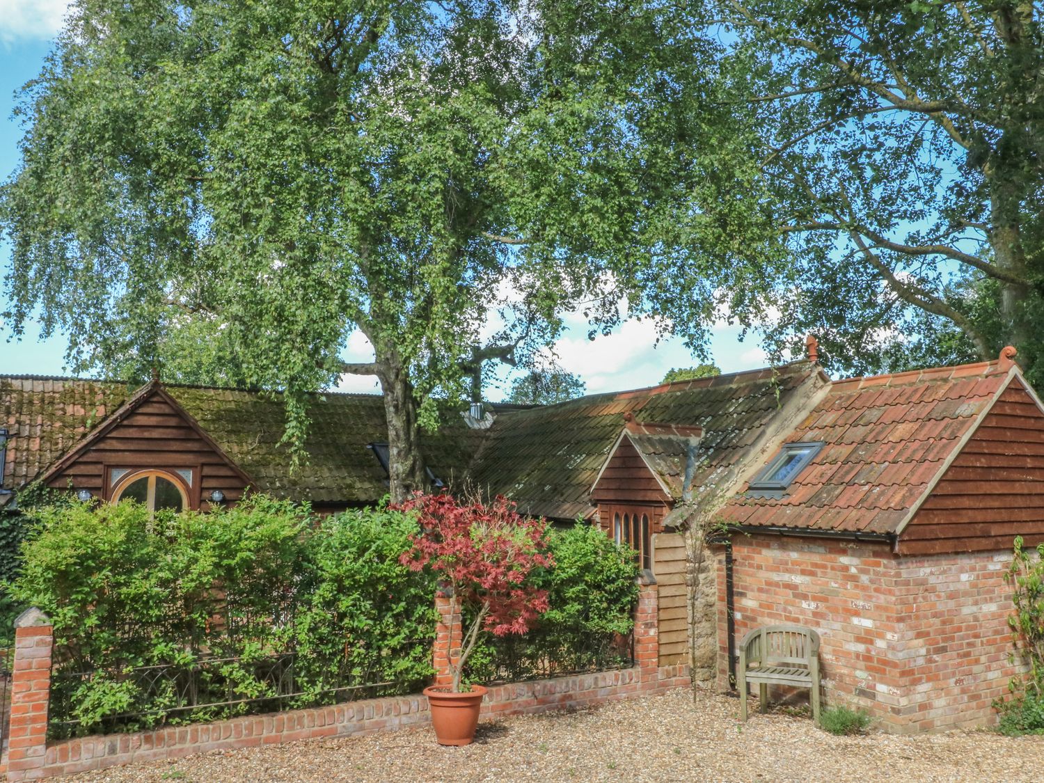 A cottage with a tiled roof trees and plants in the yard at The Hemmel in Faringdon