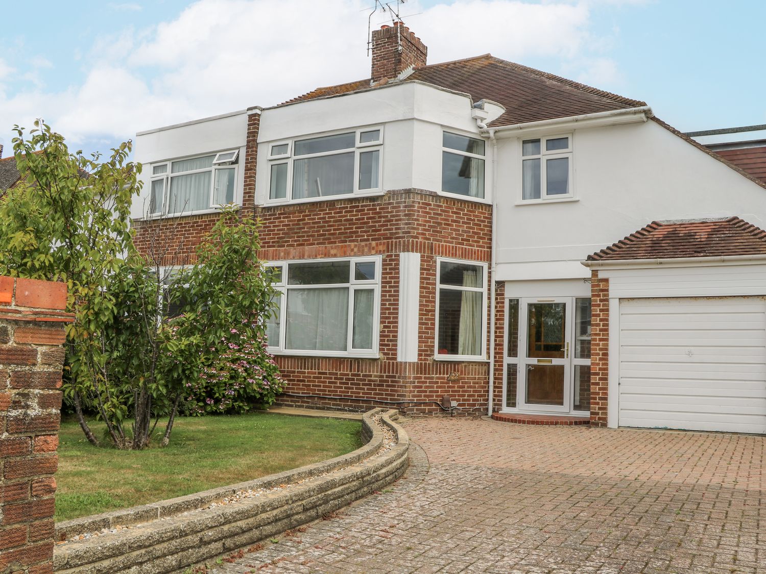 A house with a garage and driveway at Sea Dreams in Goring-By-Sea