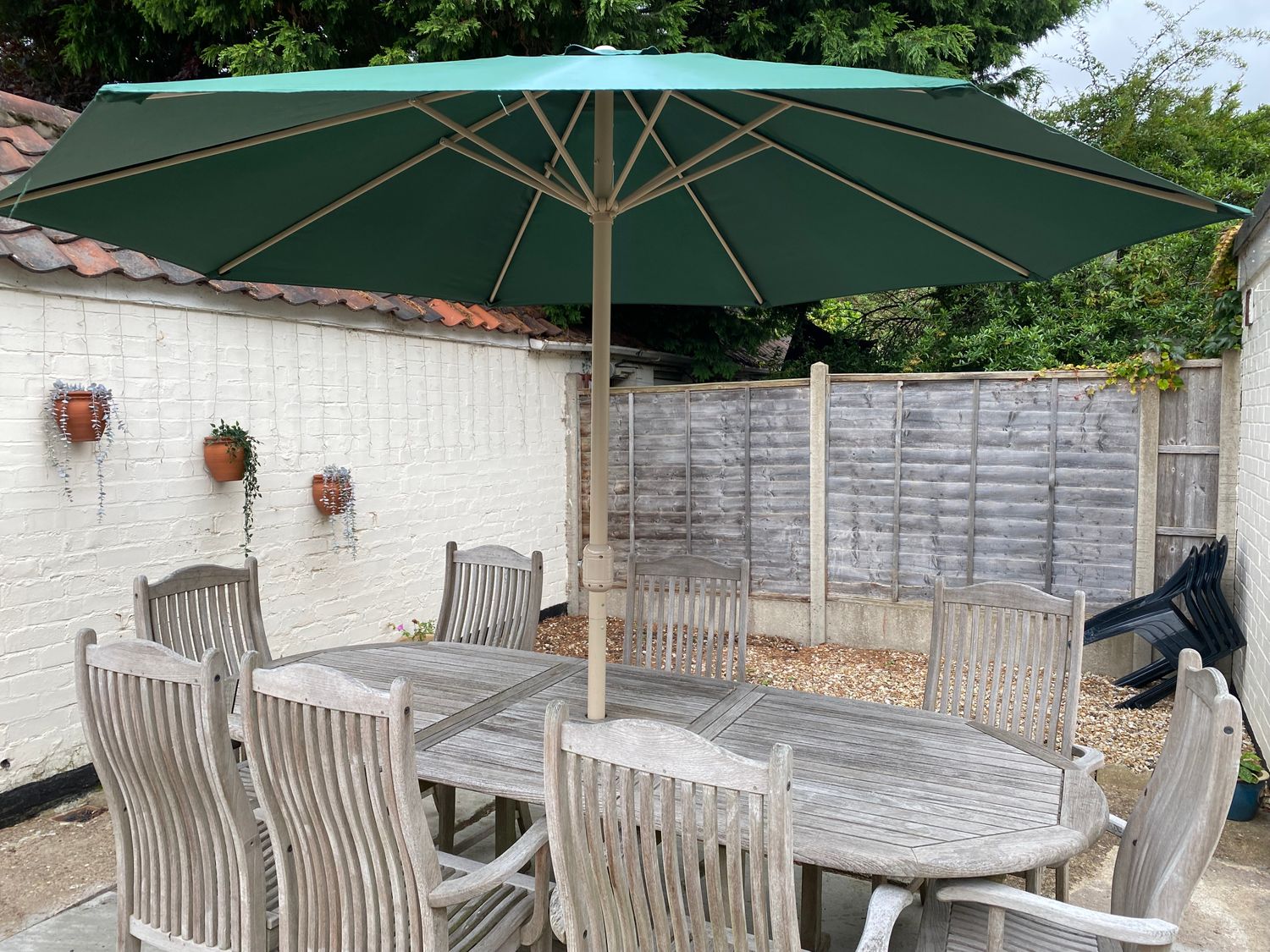 An outdoor dining area with a wooden table and chairs under a green umbrella at Lincoln House in Lincoln
