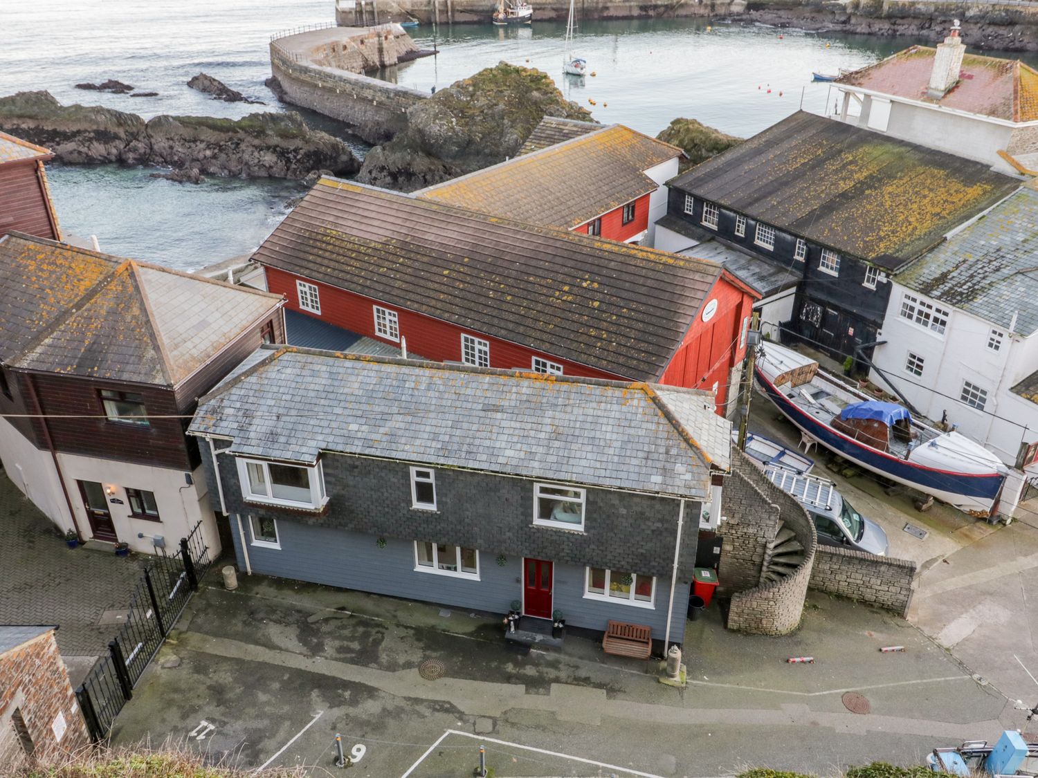 A coastal village with houses near rocky shore and a boat on land at Casa Del Mar in Mevagissey