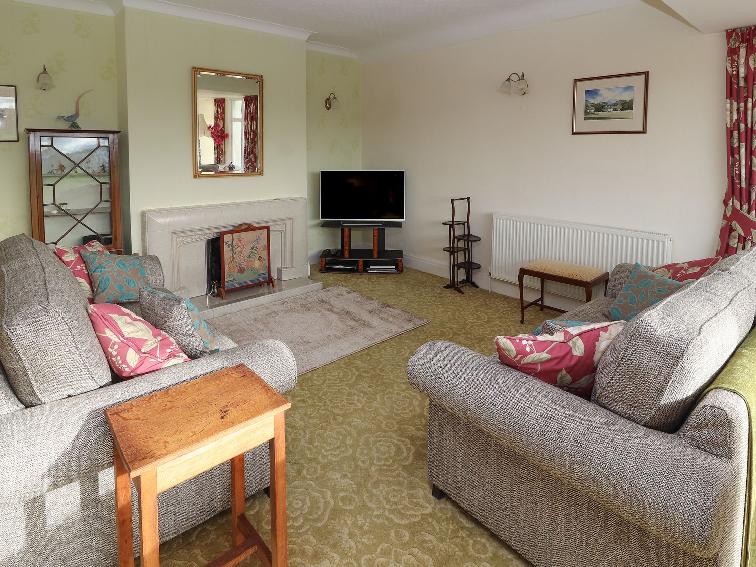 A living room with two sofas a television on a stand a fireplace and a wooden side table at The Yatt in Rhos-On-Sea