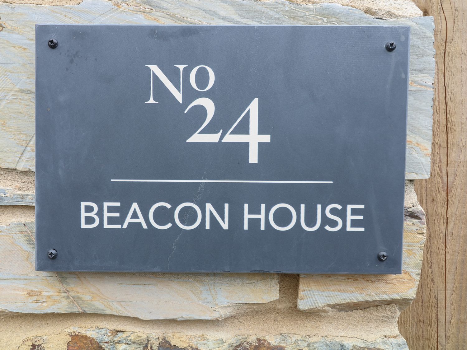 A house number plaque reading No 24 Beacon House mounted on a stone wall at Beacon House in St Agnes