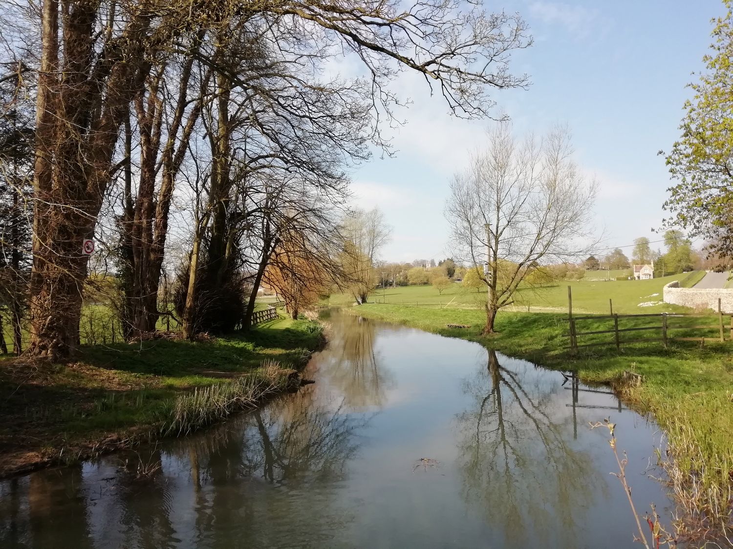 A river with trees on both sides and green fields in a rural area at 3 Painters Field Quenington Near Cirencester