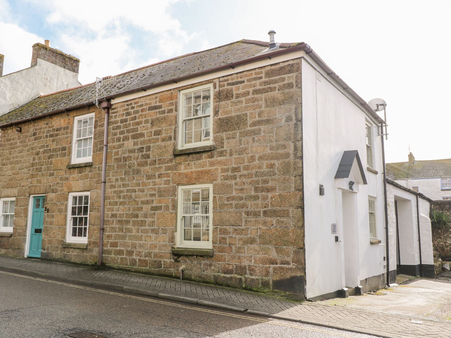 A stone and white painted cottage with multiple windows and a teal door at 21 Alverton Street in Penzance