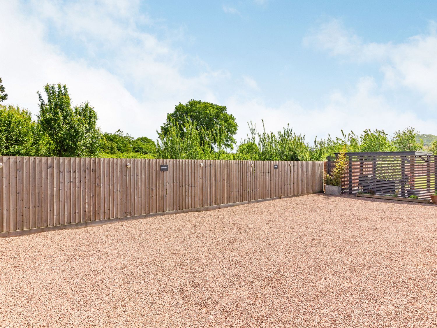 An outdoor area with gravel ground a wooden fence and a fenced seating area at 2 Stanley Villas in Hereford