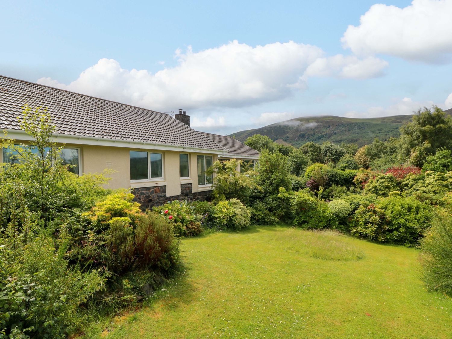 A house with a garden and mountains in the background at Knockendoch in New Abbey