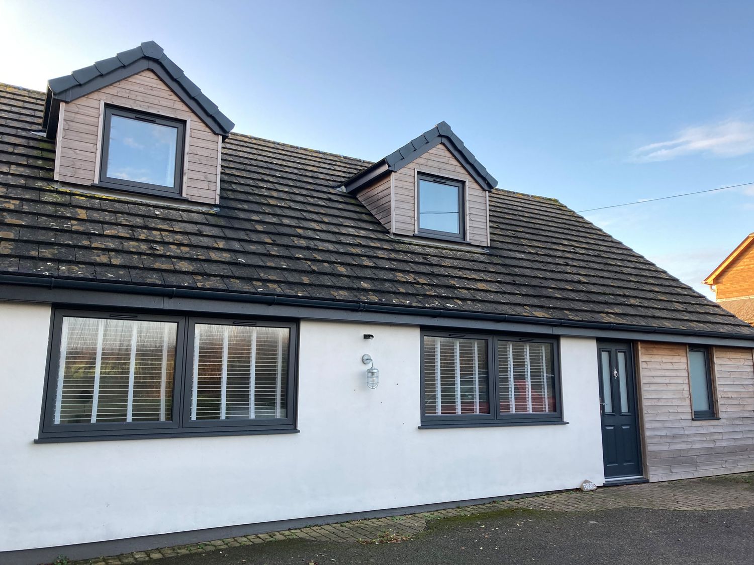 A front view of a house with two dormer windows two ground floor windows and a door at Fairways Stibb near Bude
