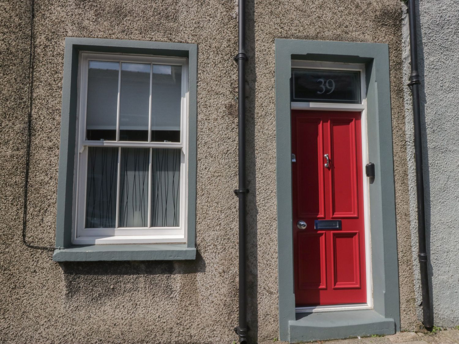 A red door and window on a textured wall at Number Thirty-Nine in Ulverston