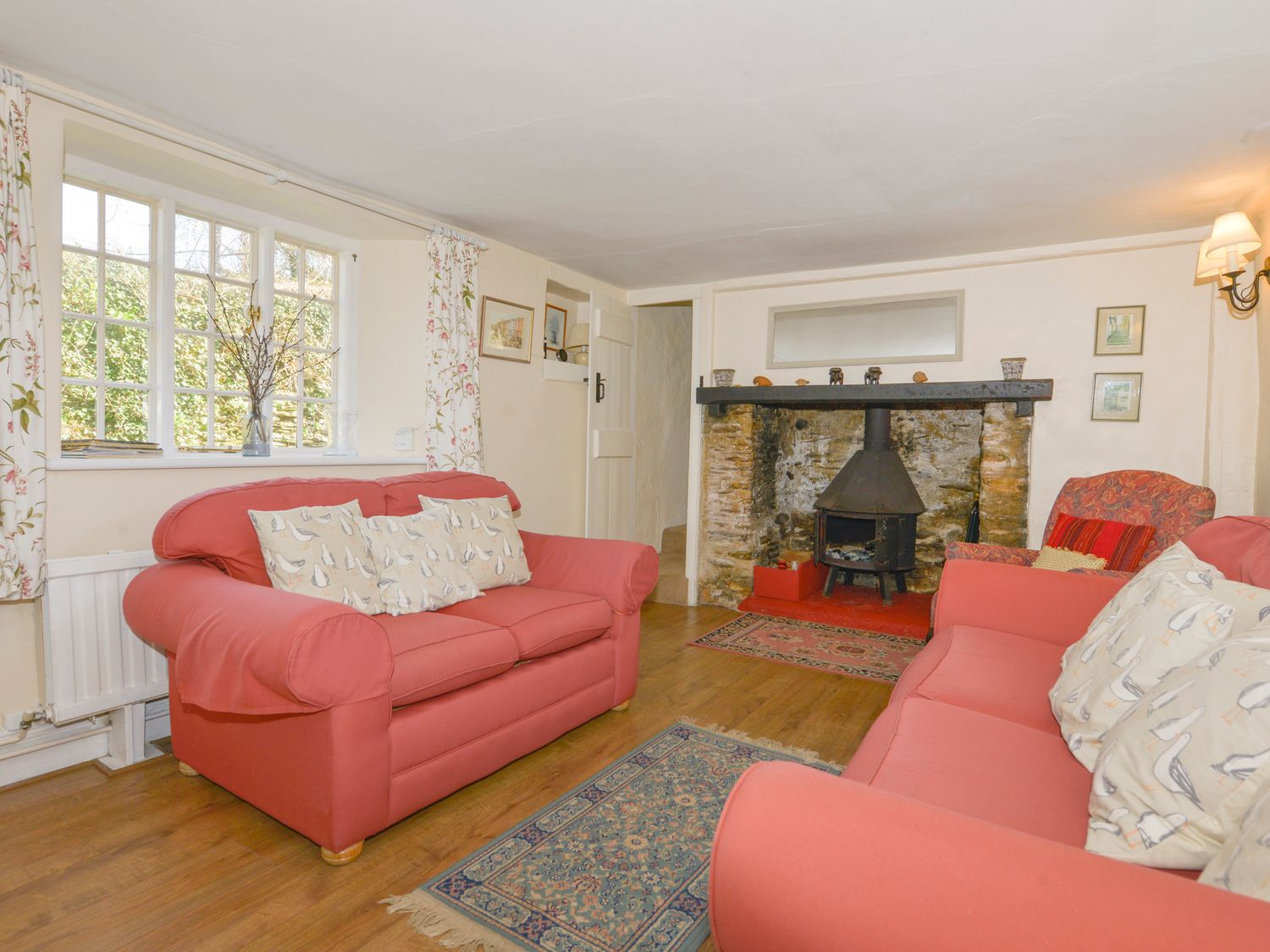 A living room with two red sofas and a fireplace at Yew Tree Cottage in Stoke Fleming