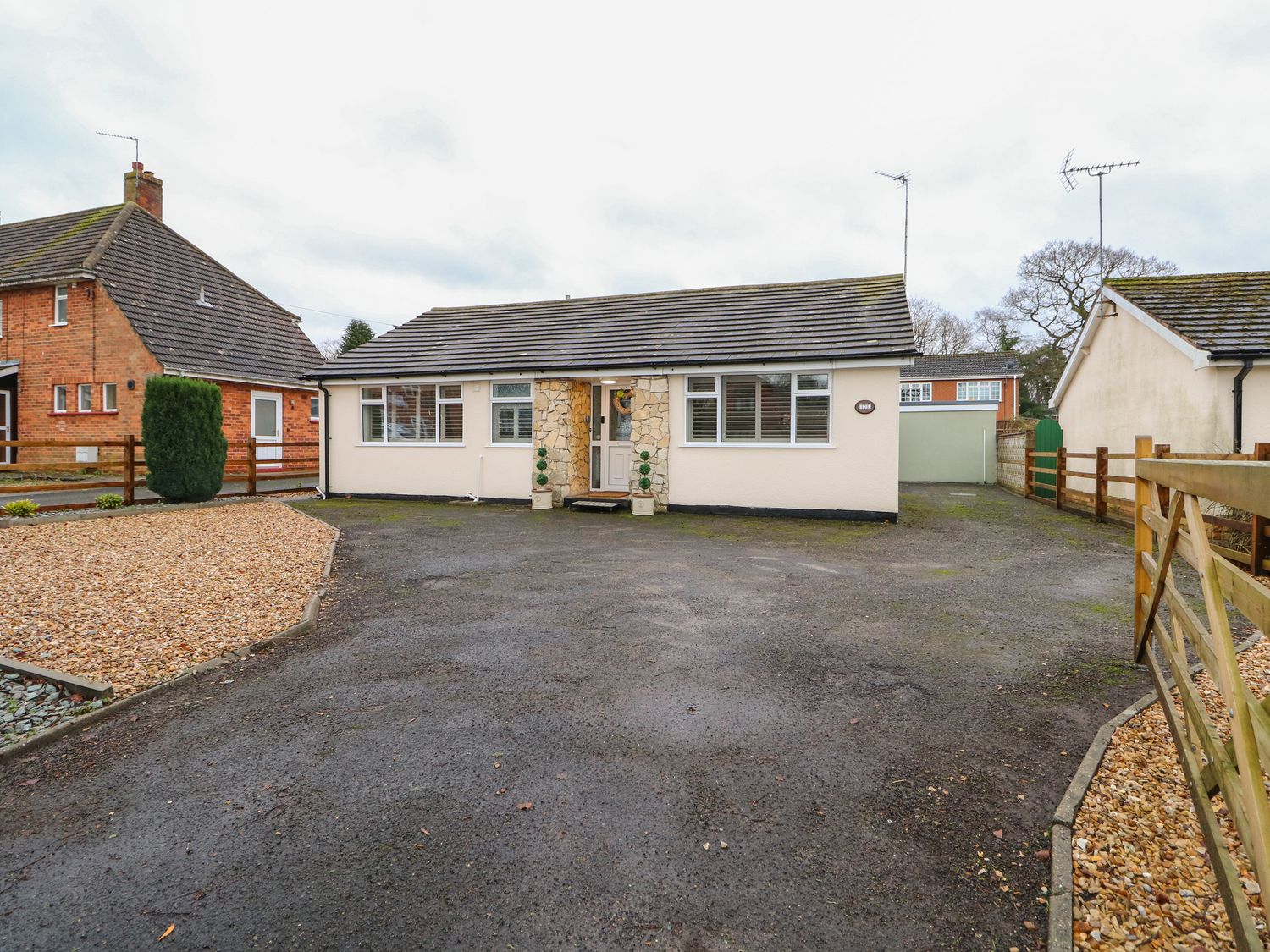 A single-story house with a paved driveway and stone facade around the front door at Giggling Goose Cottage in Woodhall Spa