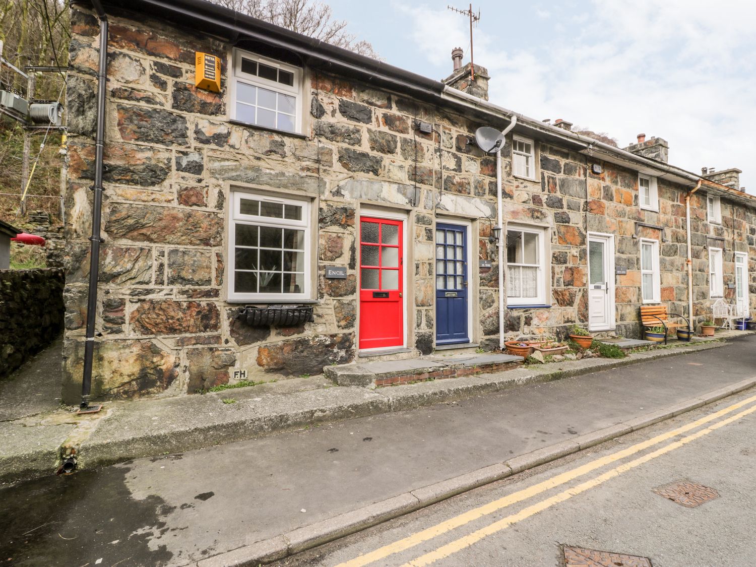 A row of stone cottages with red and blue doors and windows along a street at Encil in Beddgelert