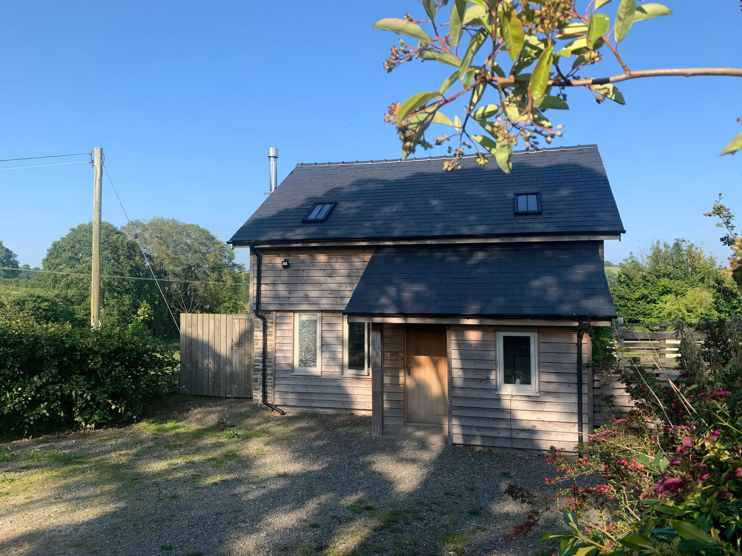 A house with a wooden door and windows at Brynlikky Cottage, Chapel Lawn near Bucknell