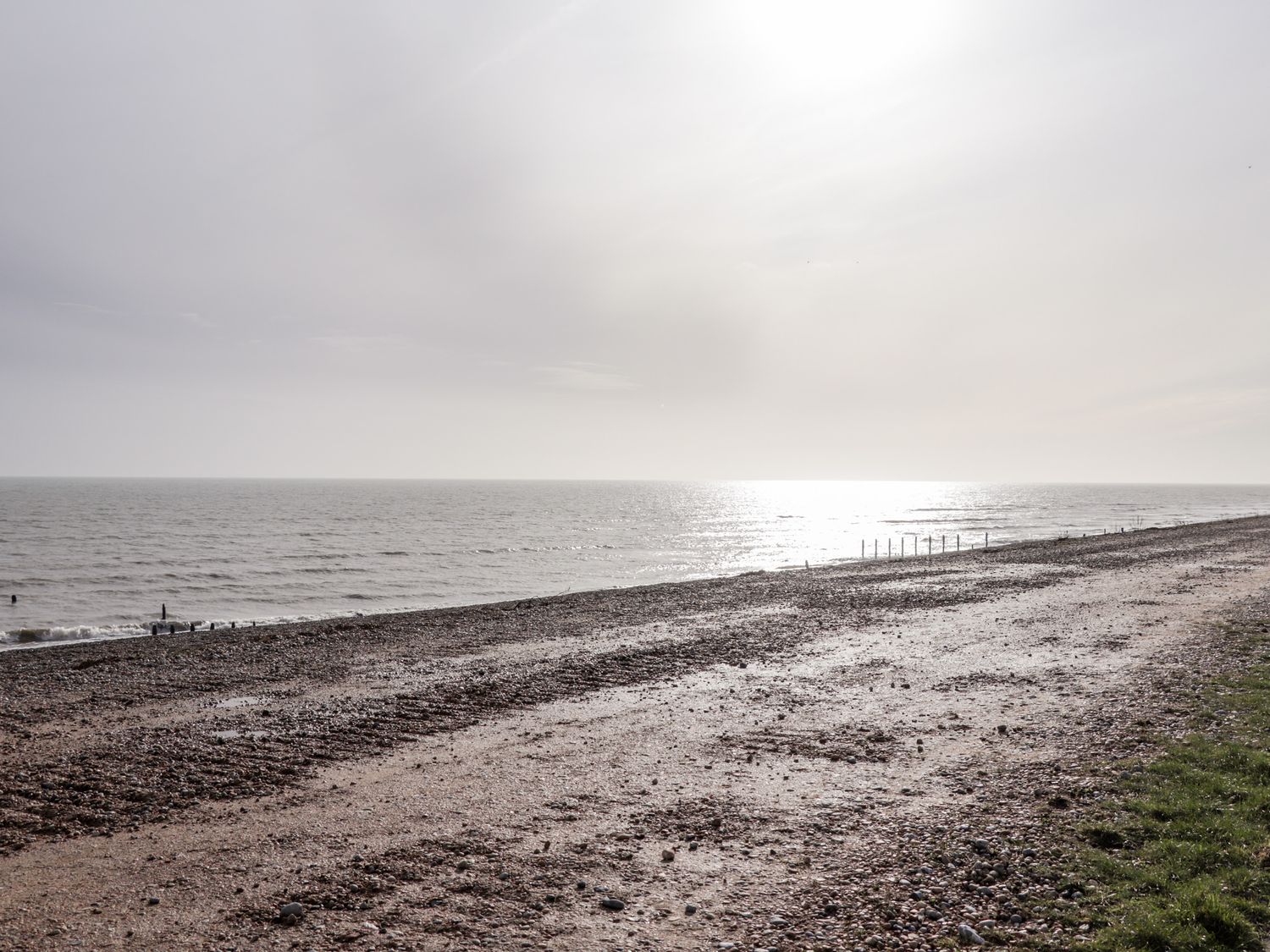 A pebbled beach with sea and sky in the background and a strip of grass on the side at Sparrows Den Lodge in Winchelsea Beach