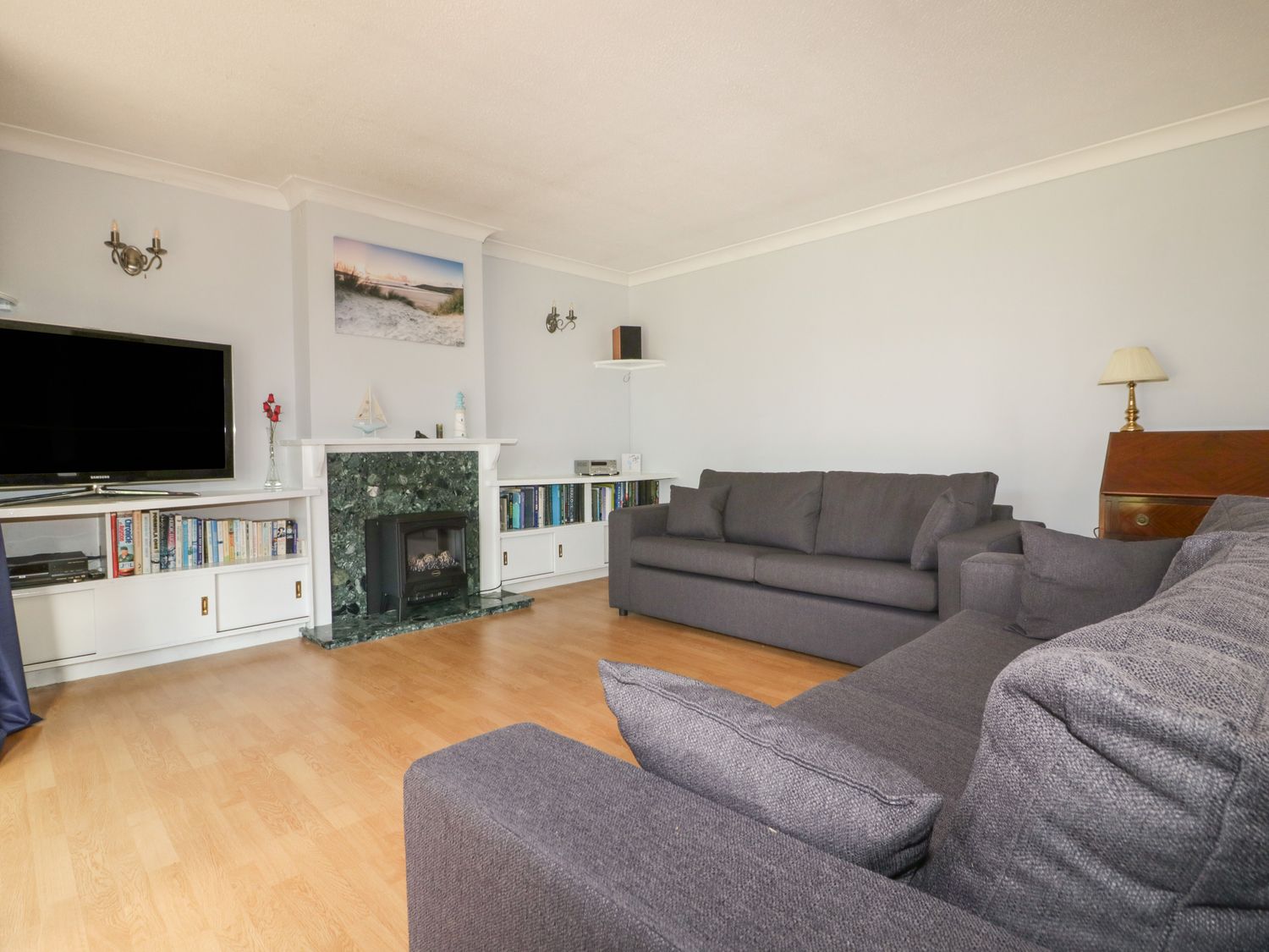 A living room with two grey sofas a television and a fireplace at Three Jays in Lanreath