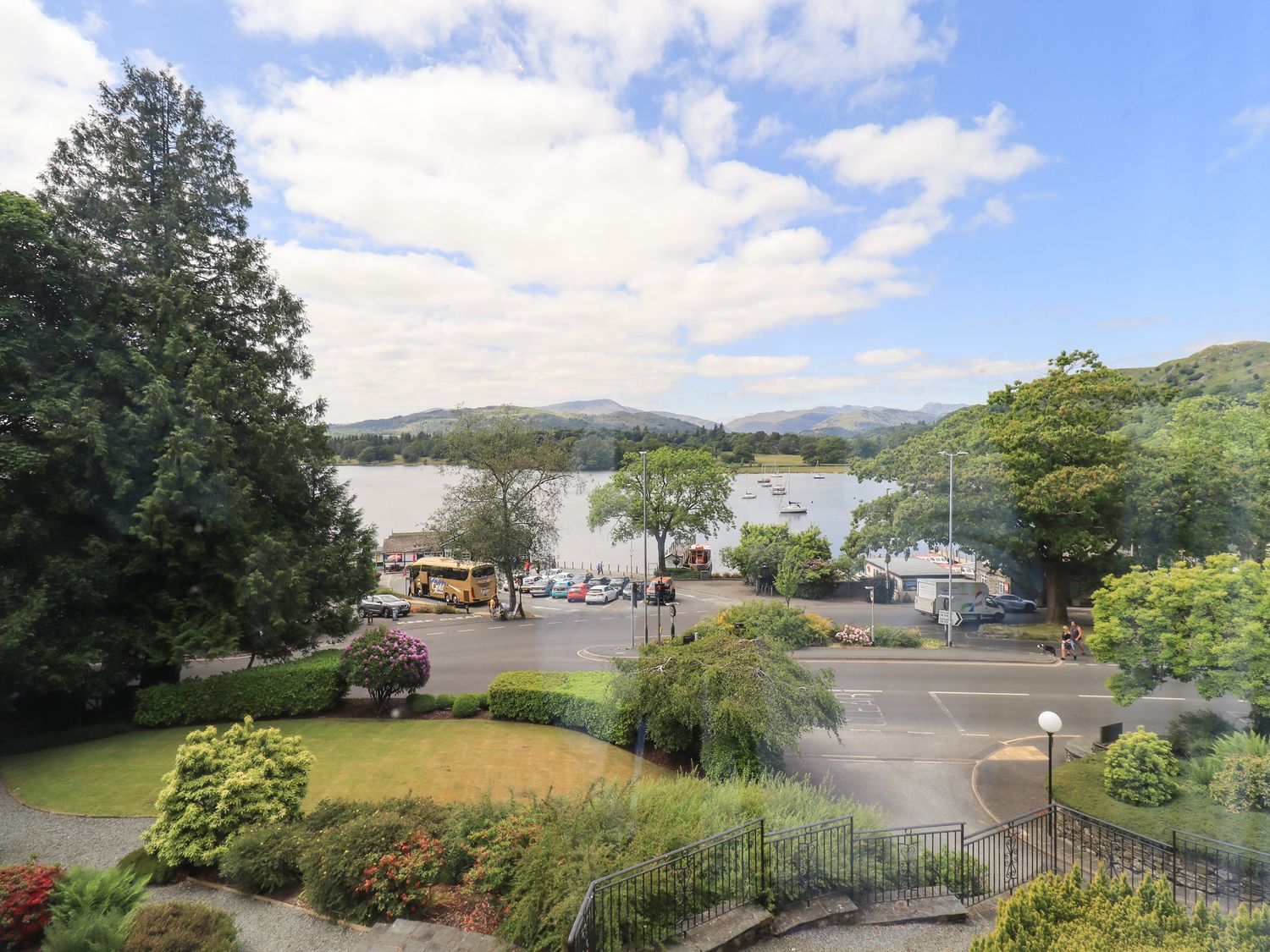 A view of a lake with boats trees a road and parked vehicles at Pure Grace in Ambleside