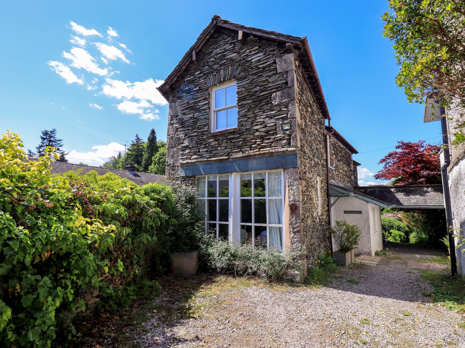 A stone house with windows and a door surrounded by bushes at Tower Cottage in Windermere