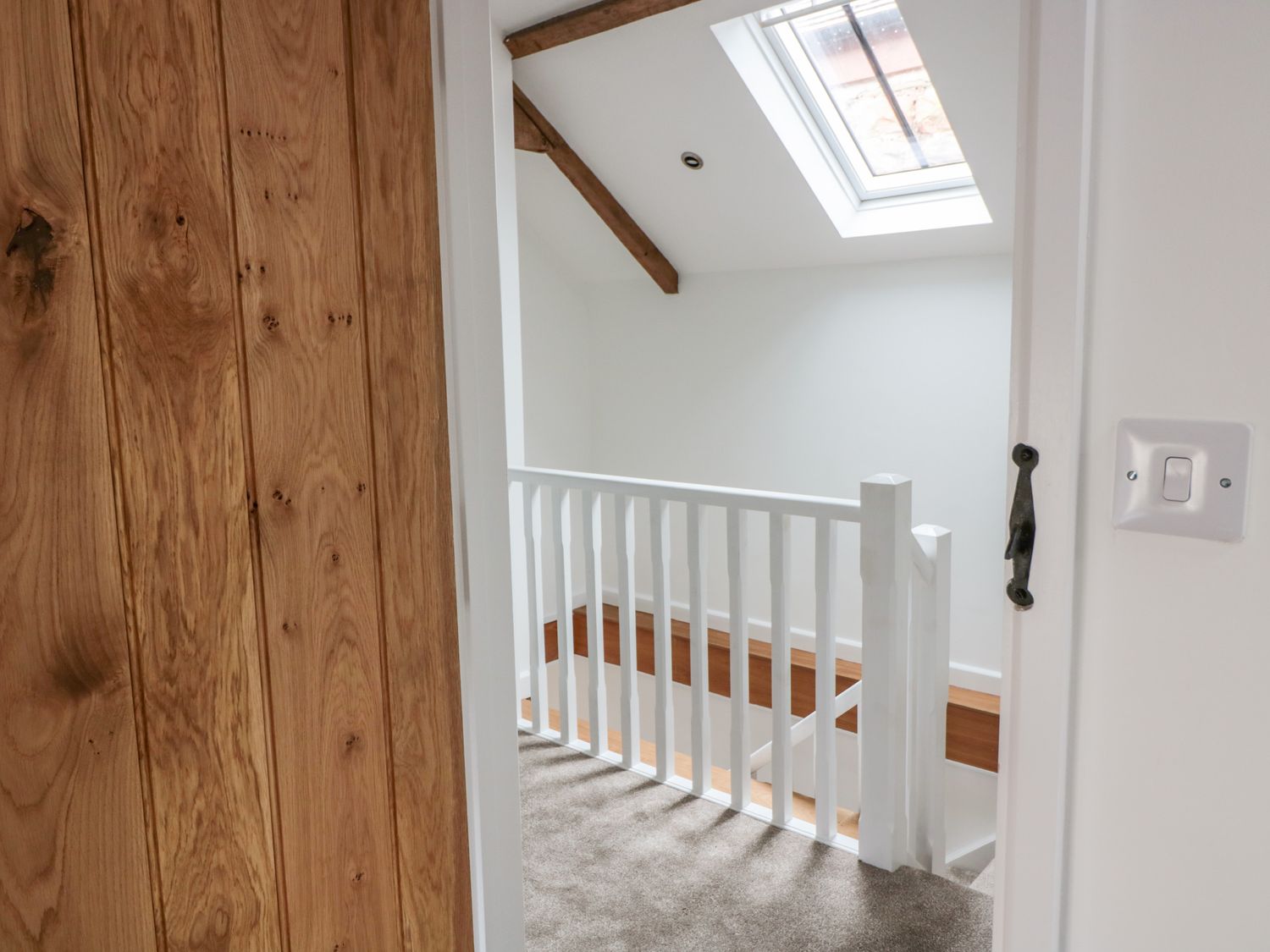 A landing with a white banister wooden beams and a skylight at Ostlers in Mitcheldean