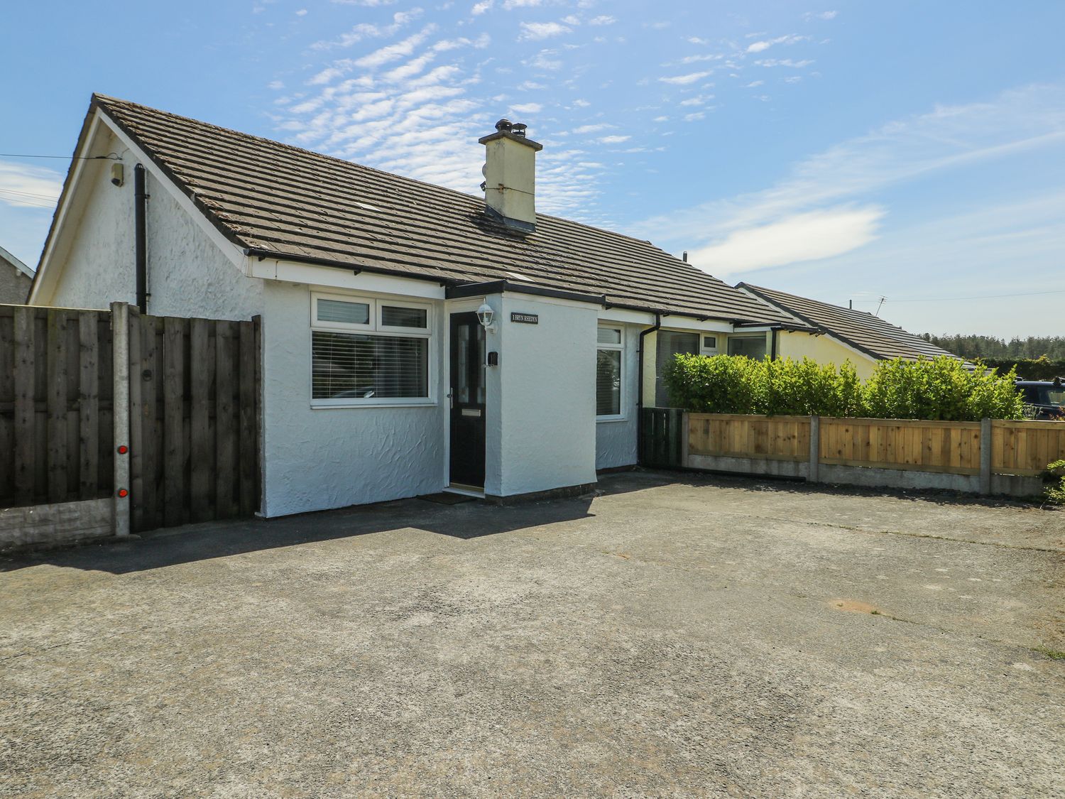 A bungalow with a driveway and fence at Fern Hill Cottage Newborough