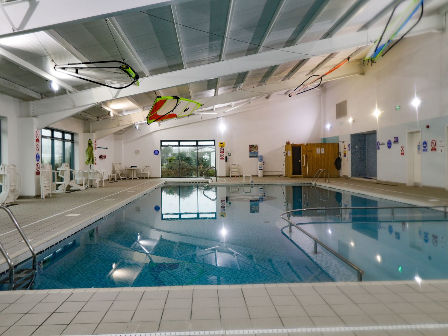 An indoor swimming pool with chairs tables and a sauna at 2 bedroom Lodge at Pevensey Bay in Pevensey Bay