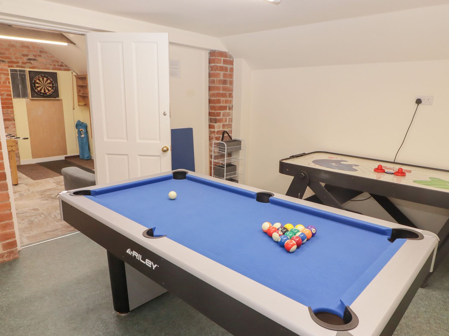 A game room with a pool table with balls set up and an air hockey table at Morawel Newport Pembrokeshire