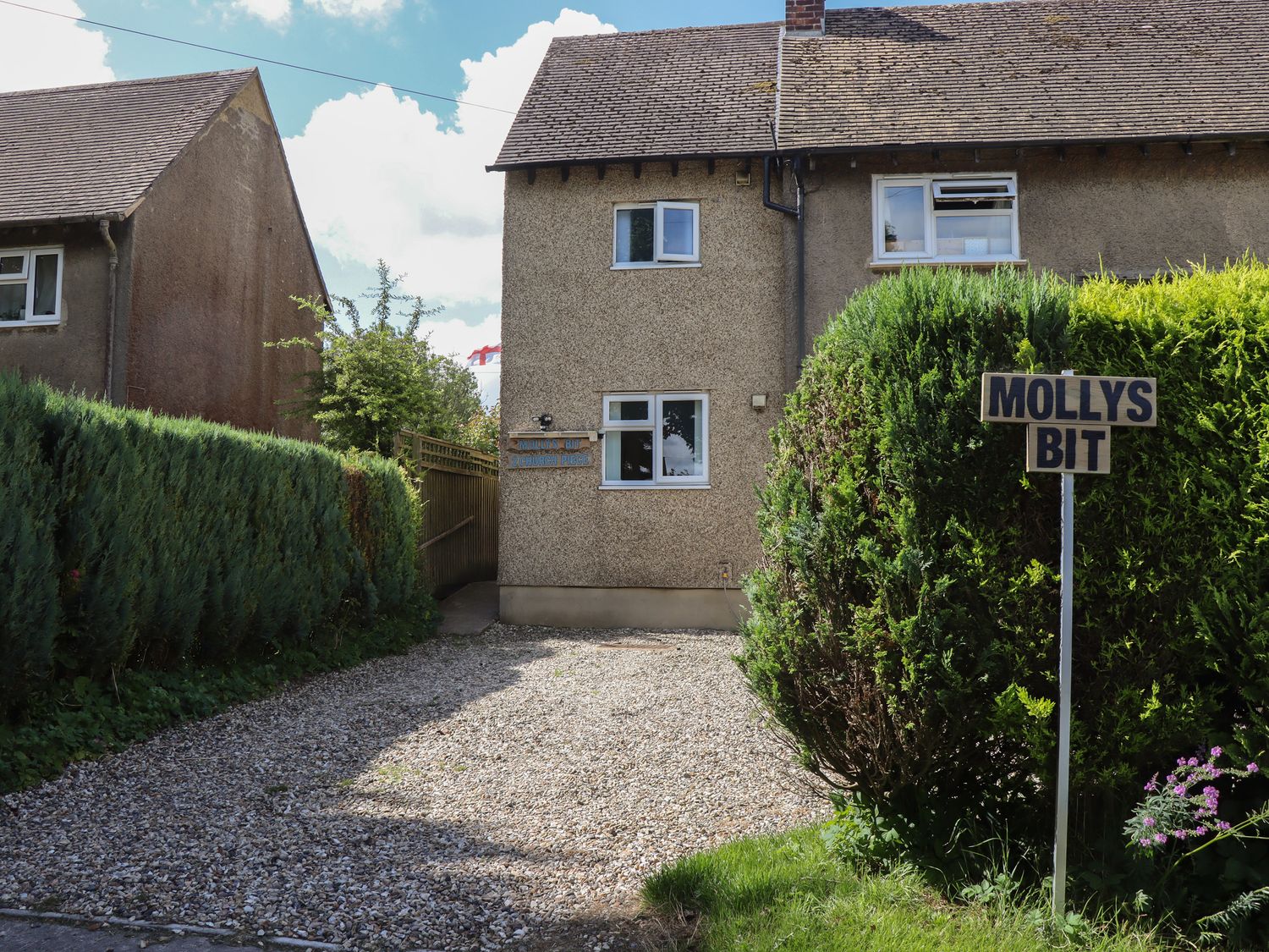 A gravel driveway leading to a two-story house with hedges on both sides at Mollys Bit Church Westcote near Bourton-On-The-Water