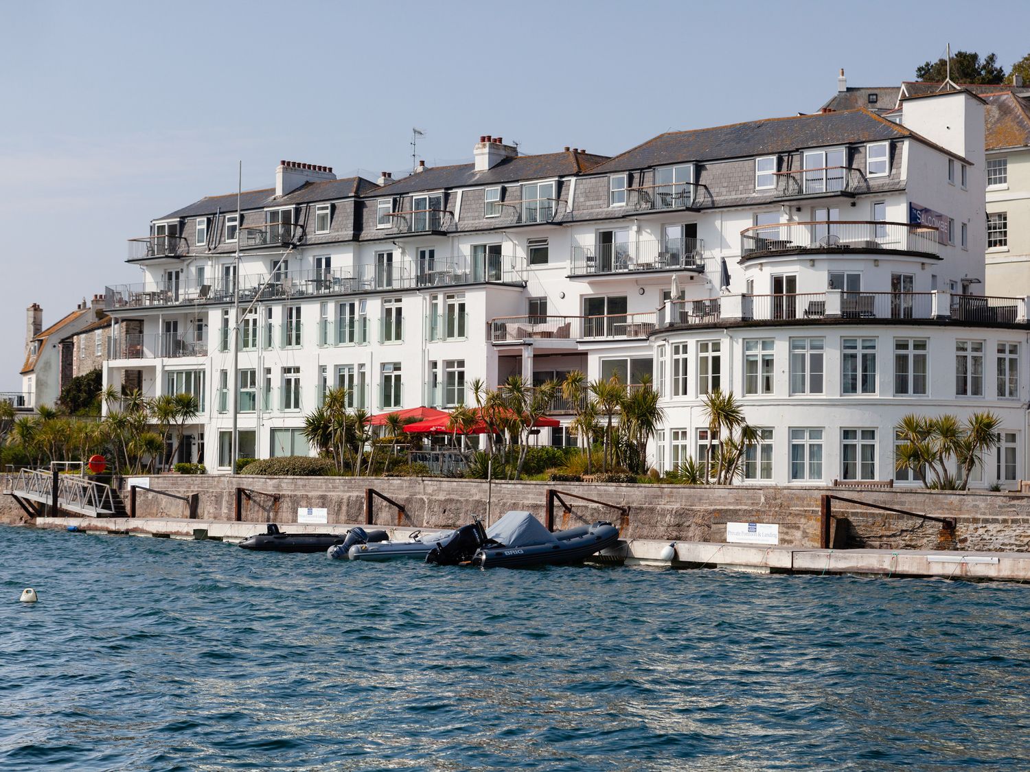 A waterfront building with balconies and small boats docked in the water at 34 The Salcombe in Salcombe