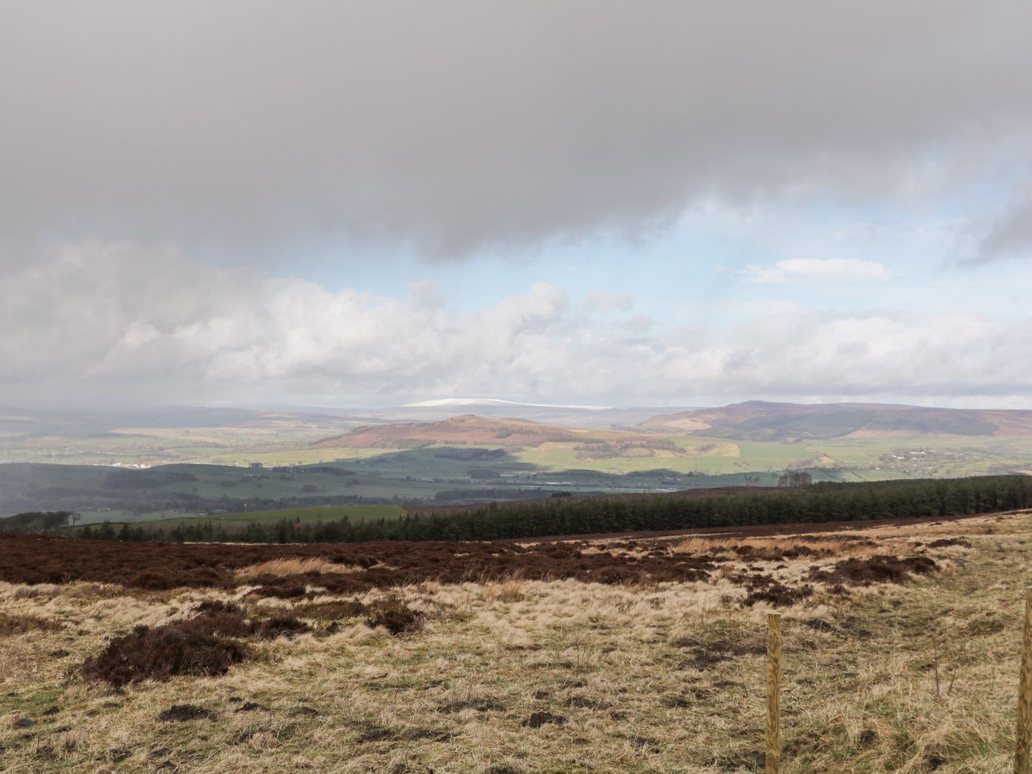 A landscape view of fields hills and forest under a cloudy sky at Crag View Cottage in Embsay