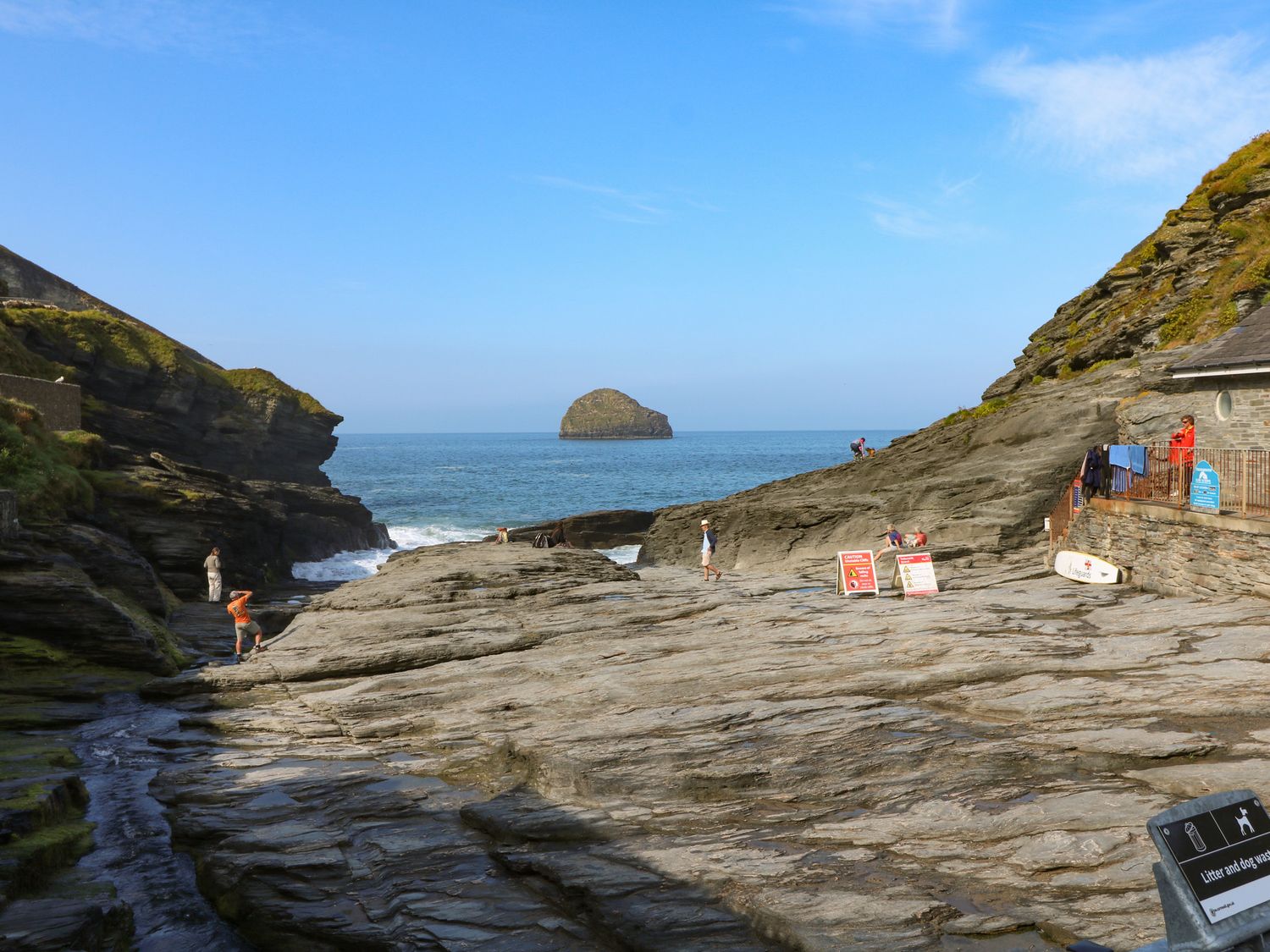 A rocky coastal area with people walking and standing near the ocean at Atlantic Cottage in Delabole near Port Isaac